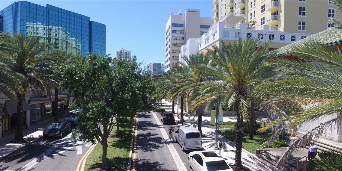 Elevated view of Downtown Clearwater's Cleveland Street, featuring palm trees, parked cars, sidewalks, and surrounding downtown buildings.