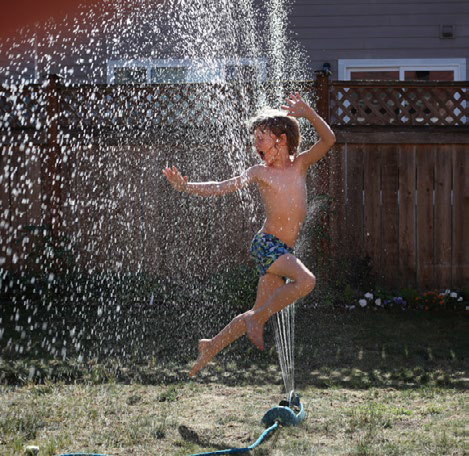 Boy playing in sprinklers