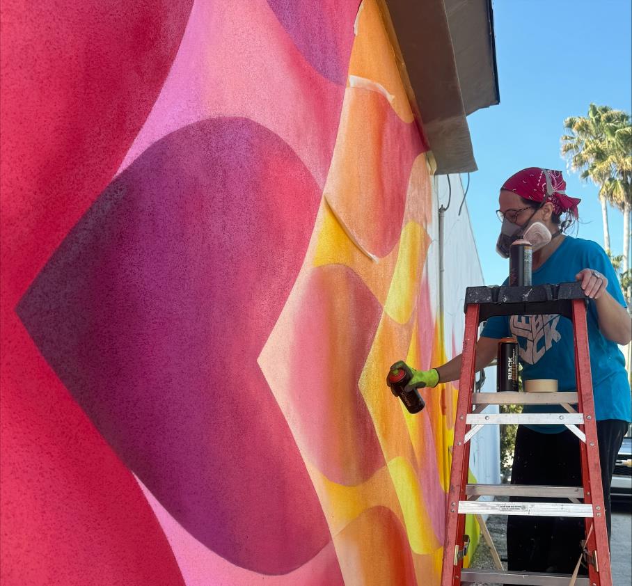 Artist spray painting an outdoor mural.