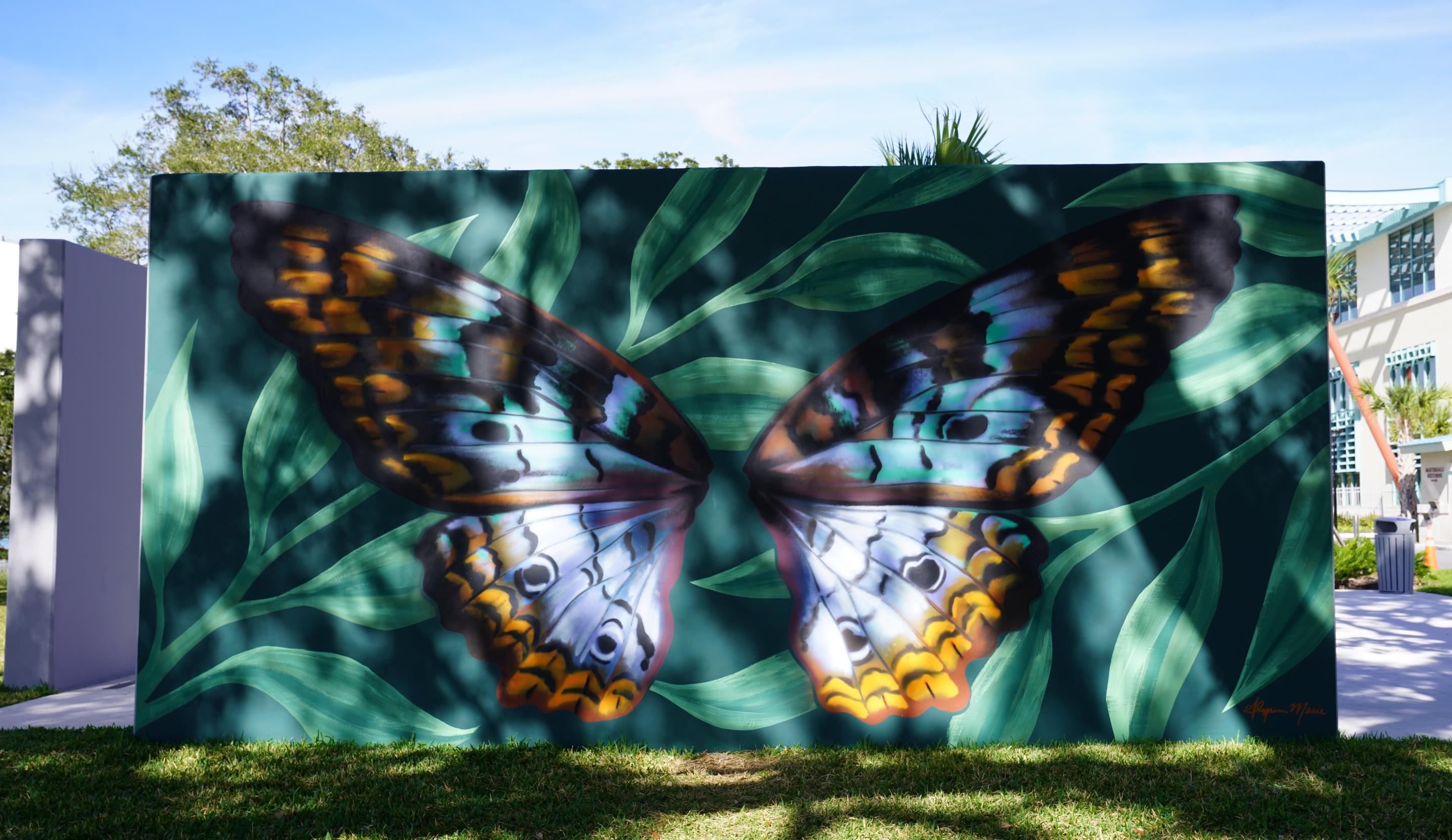 Wall mural of butterfly on green leaves