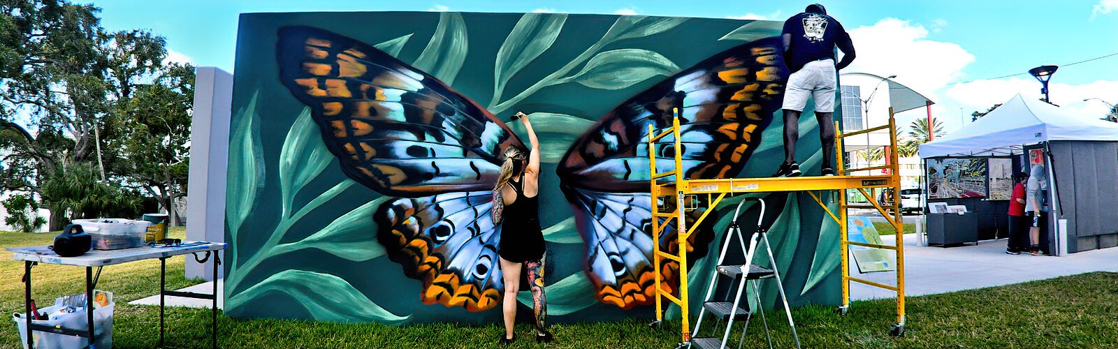 Image of two artists working on butterfly mural