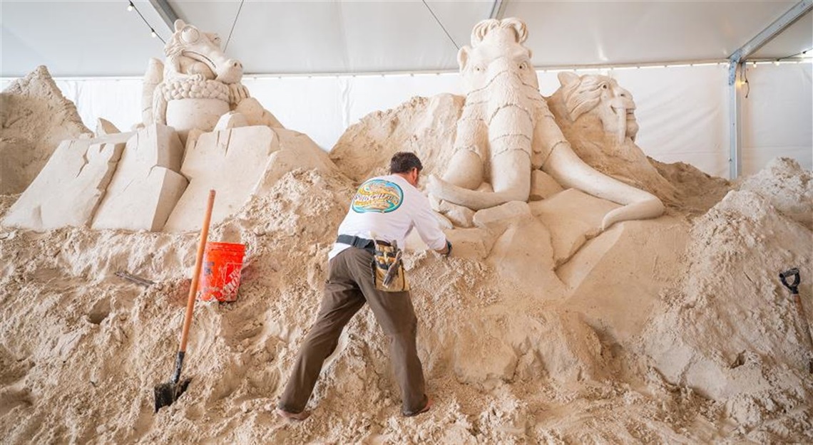 A sculptor is shown carving sand sculptures at Clearwater Beach