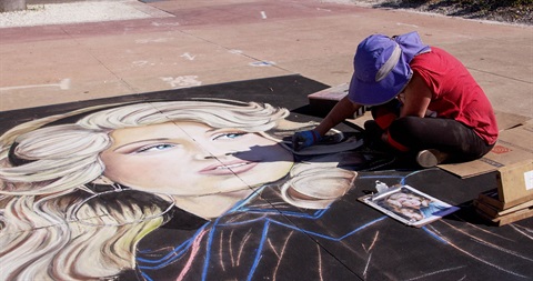 a man drawing chalk art on the ground