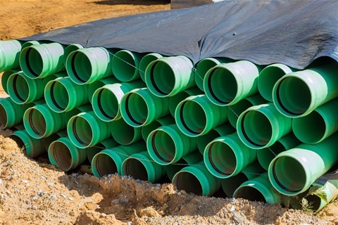 Green pipes stacked and covered with a tarp.