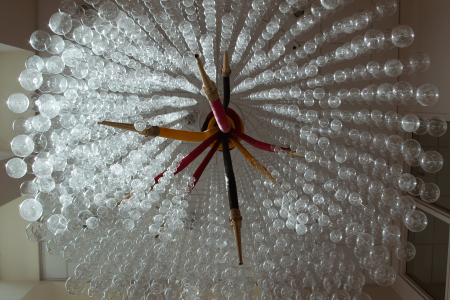 Looking up at a chandelier made of fire hoses and clear glass balls.