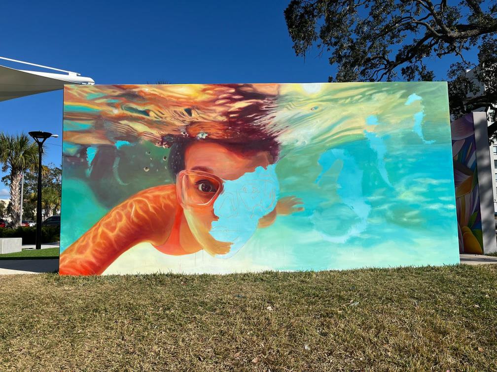 Unfinished outdoor mural of a mermaid underwater.