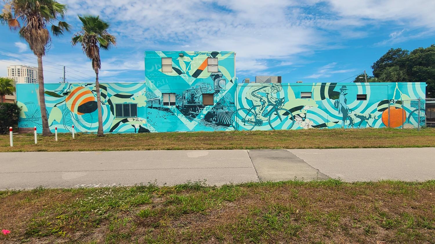Exterior mural on a building with bicycles and steam engines denoting progress.