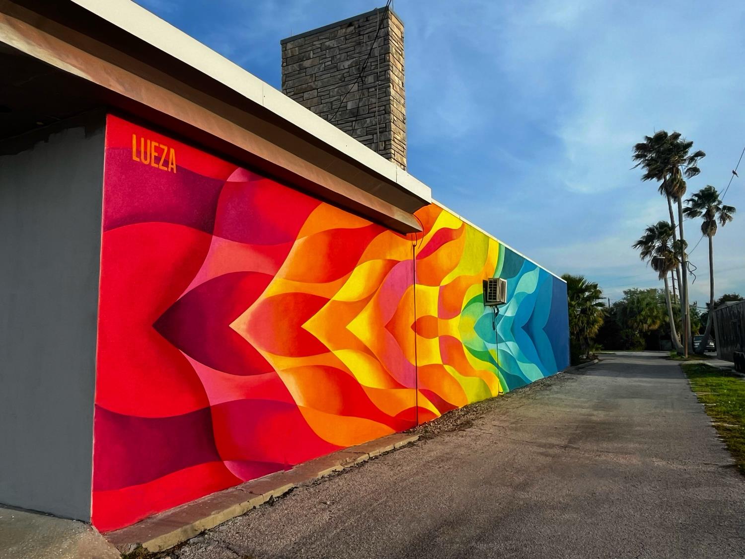 Outdoor wall mural of multi colored waves from red to blue.